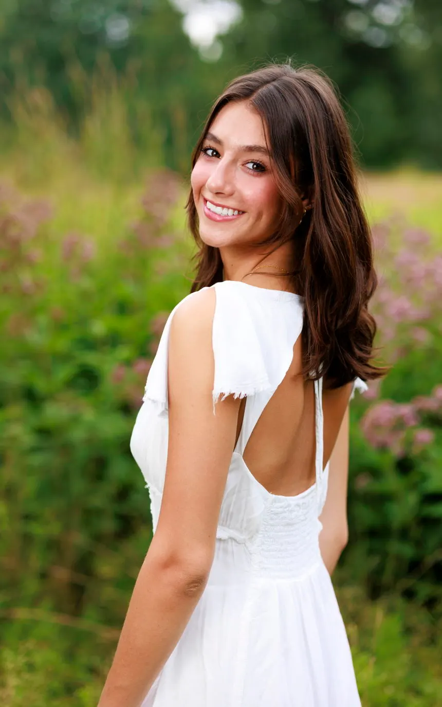 A young woman in a white dress looking back over her shoulder