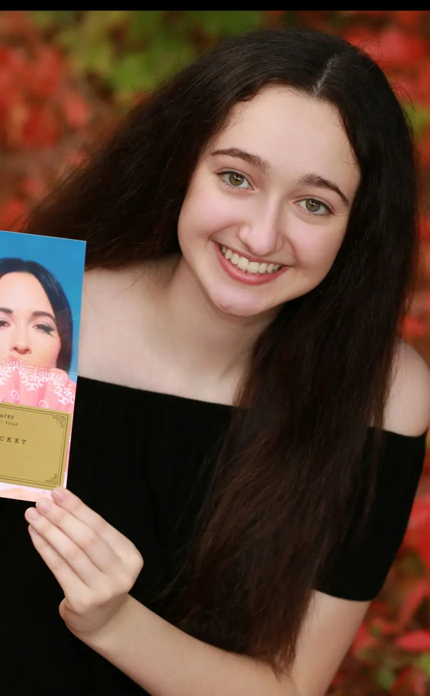 A smiling senior holding up a printed photo of herself