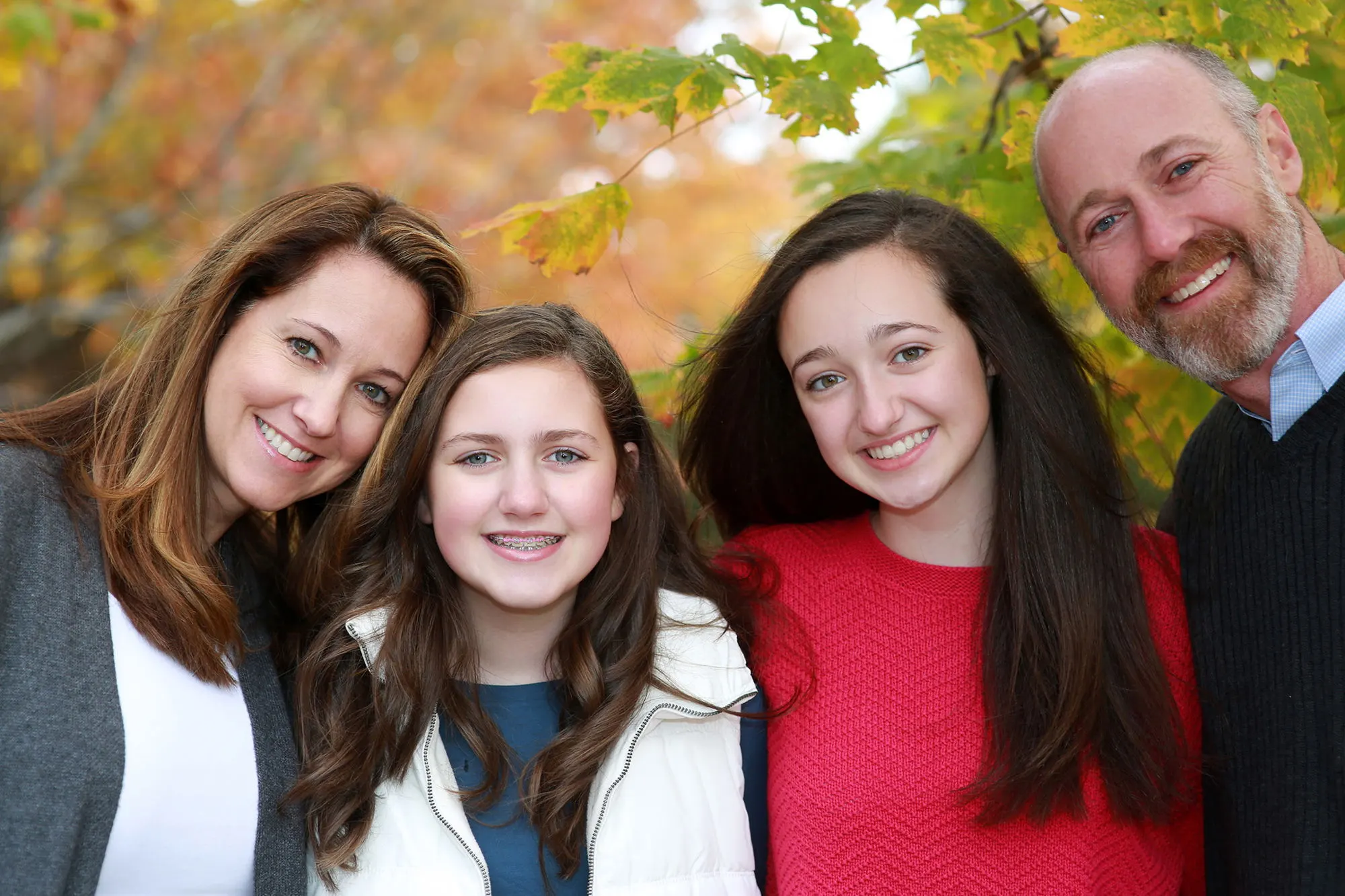 Parents and two daughters laughing together outdoors in the fall
