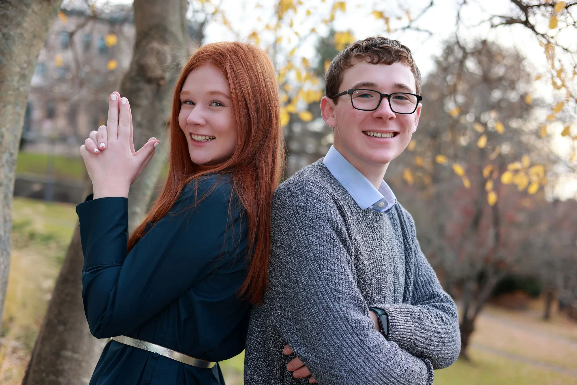 A sister and brother posing playfully in a park